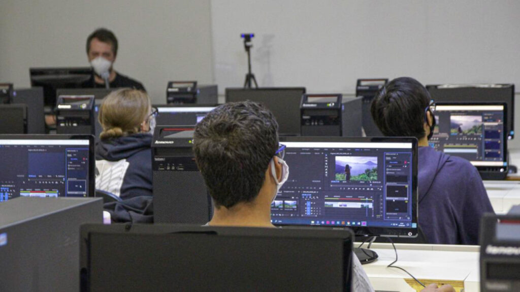 Alunos participam de oficina de edição de vídeo em laboratório de informática.